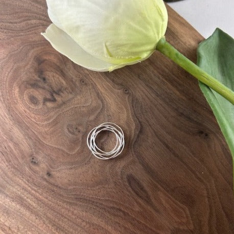 Five intertwined rings, symbolizing the unbreakable bond between family members. Handcrafted on an 18” silver chain.