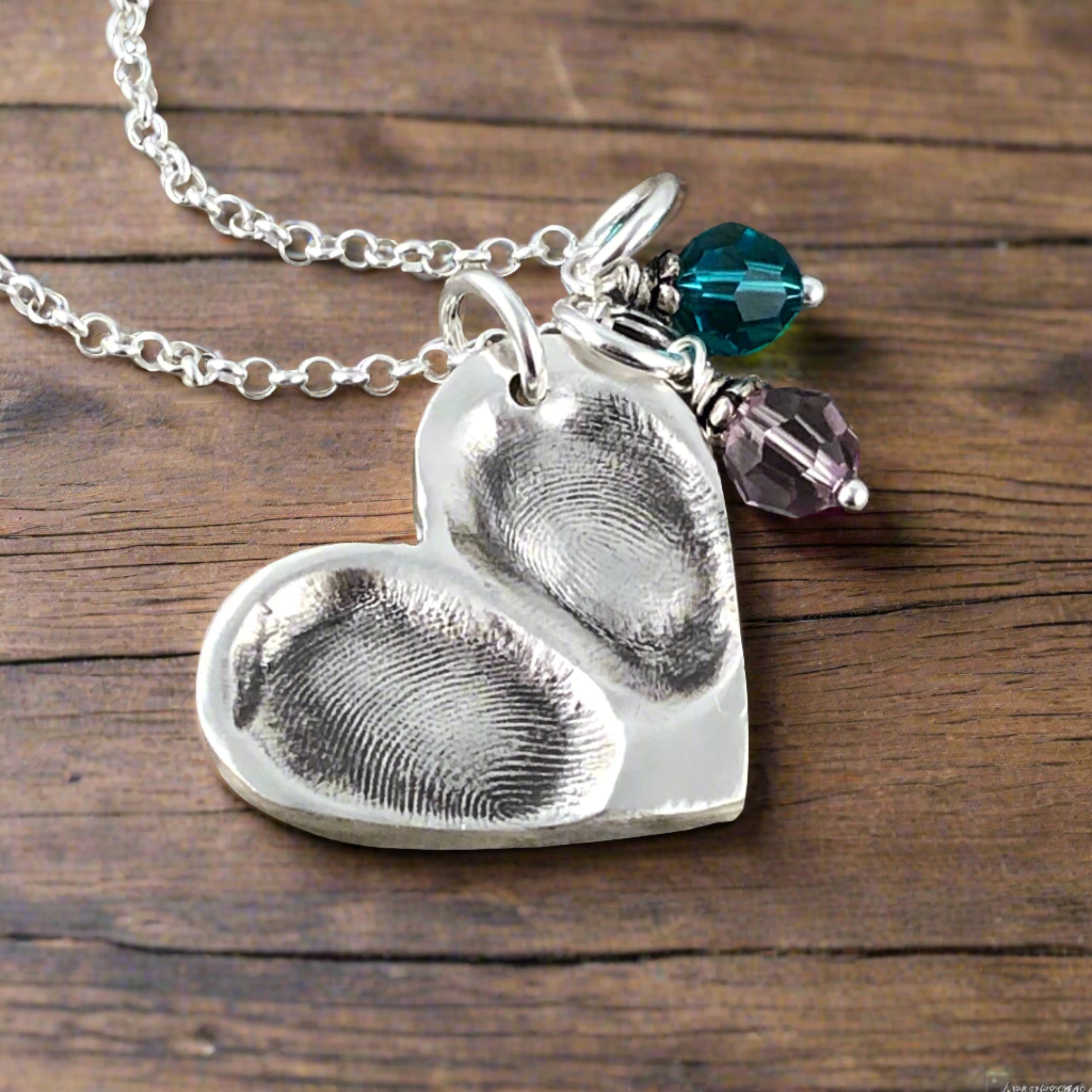 Handcrafted heart shaped fine silver pendant featuring 1-3 loved ones' prints, a modern alternative to a family ring for a sentimental and timeless keepsake.
