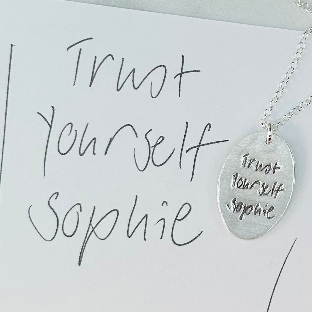 Handcrafted oval pendant showcasing a short handwritten message. Personalize with up to 10 letters from a loved one’s writing or your own design.