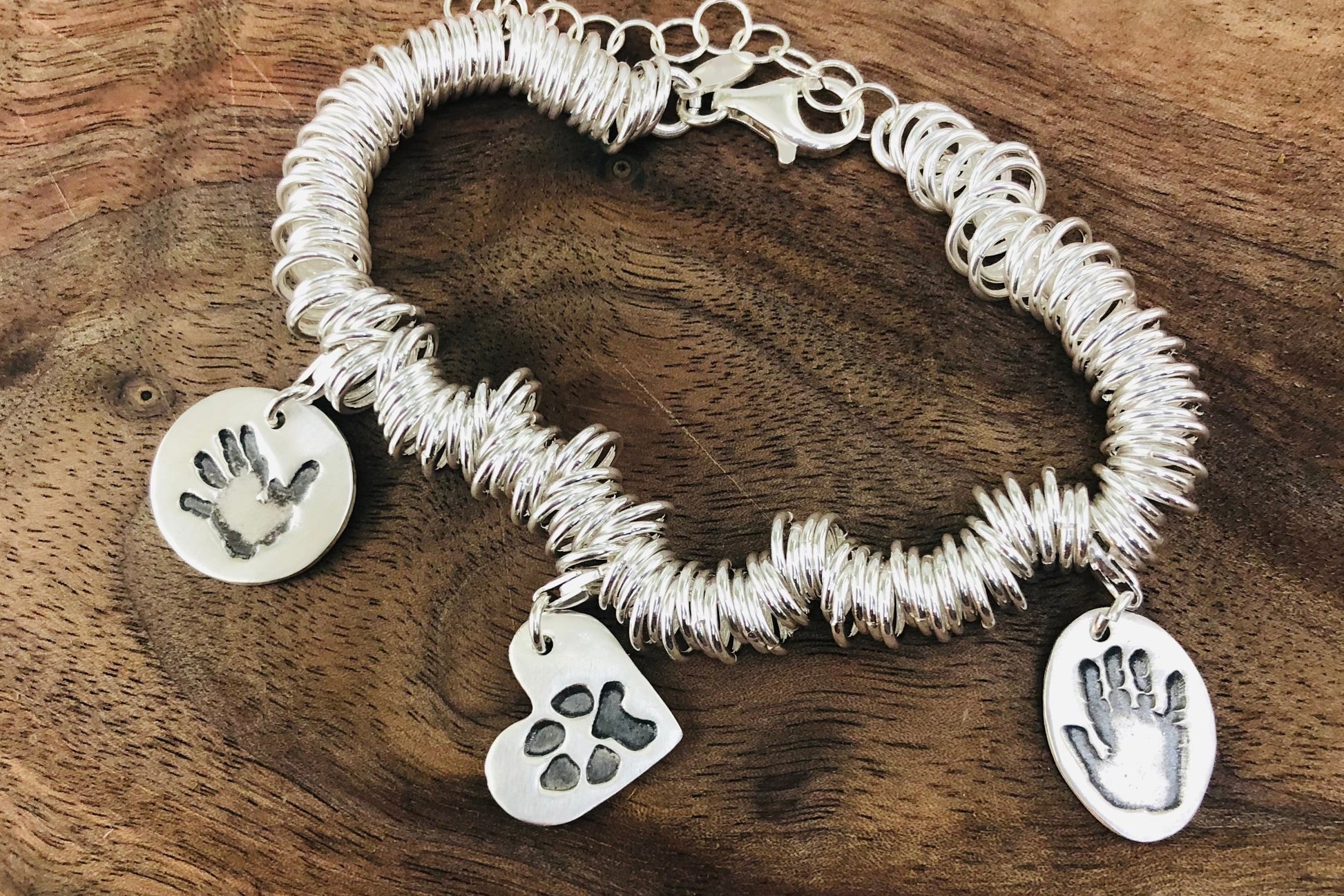 Sterling silver charm bracelet featuring hundreds of rings for elegant movement. Customizable with charms on lobster clasps for easy arrangement.