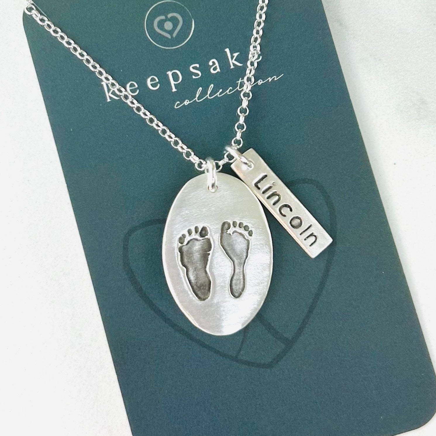 Custom fine silver oval pendant displaying real hand and/or footprints. Personalize with one or two prints and add an optional chain or embellishment.