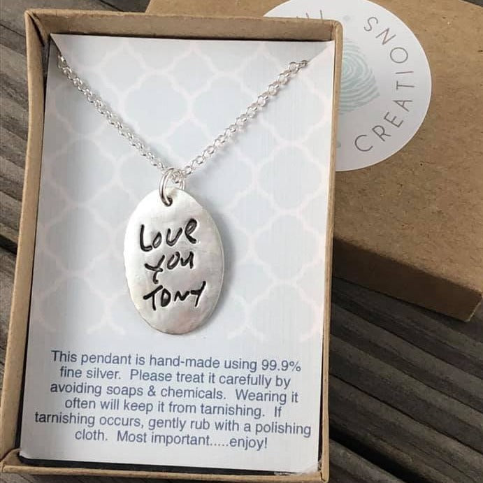 Handcrafted oval pendant showcasing a short handwritten message. Personalize with up to 10 letters from a loved one’s writing or your own design.