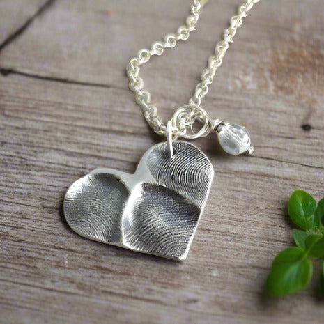 Handcrafted heart shaped fine silver pendant featuring 1-3 loved ones' prints, a modern alternative to a family ring for a sentimental and timeless keepsake.
