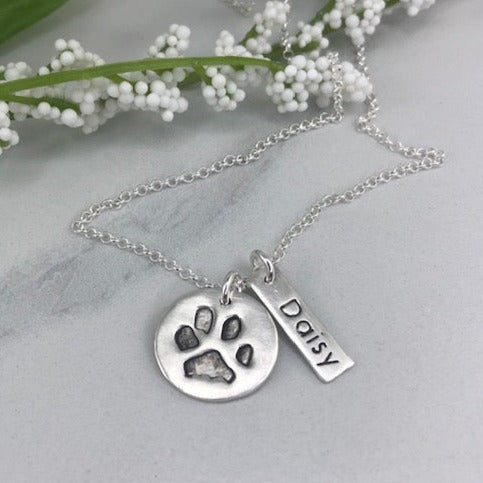 Small handcrafted fine silver circle pendant featuring a pet’s actual paw print, a meaningful keepsake to honor and cherish your furry friend.