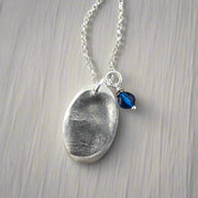 Oval fingerprint pendant crafted in fine silver, featuring a detailed replica of a fingerprint for a unique and personalized keepsake.
