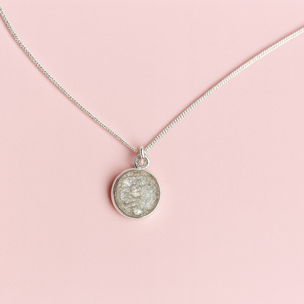 Silver necklace with a round pendant on a pink background