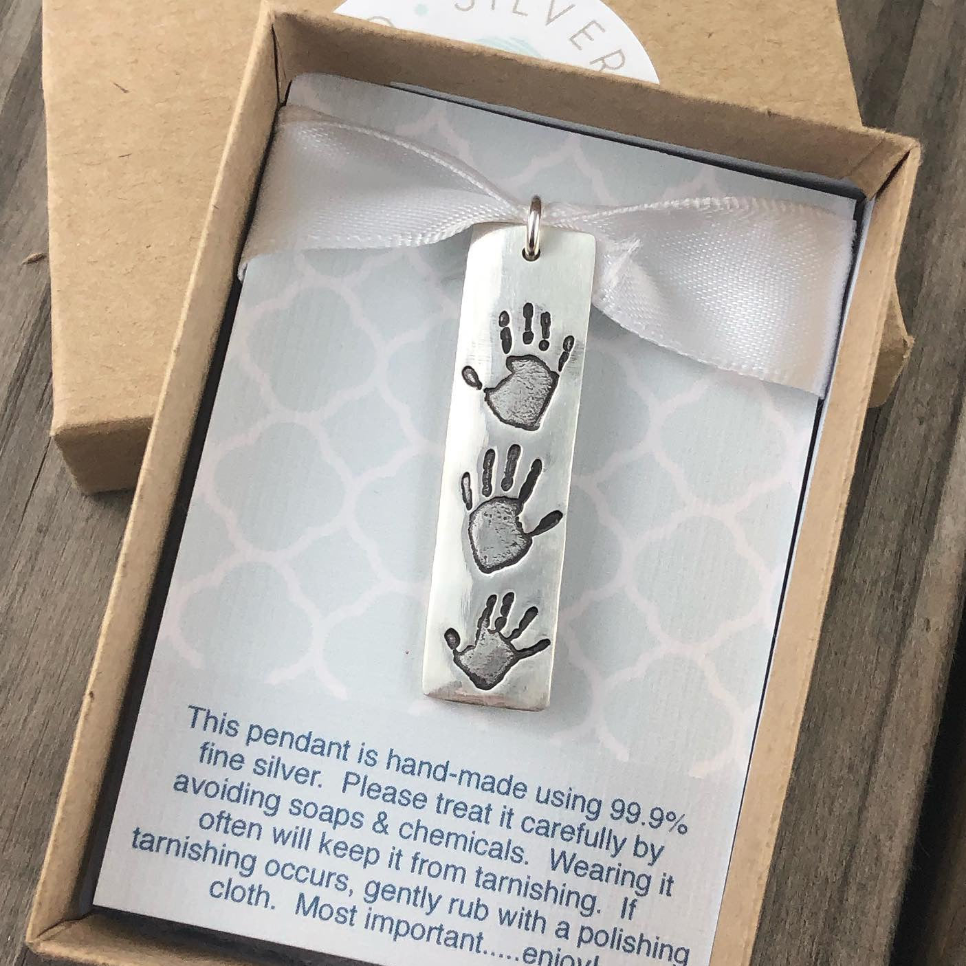 Handmade fine silver rectangle shaped pendant featuring up to 3 actual hand and/or footprints of a loved one. Customize with an optional chain or embellishment for a special touch.