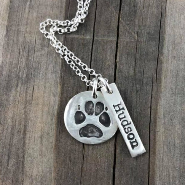 Small handcrafted fine silver circle pendant featuring a pet’s actual paw print, a meaningful keepsake to honor and cherish your furry friend.