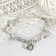 Sterling silver charm bracelet featuring hundreds of rings for elegant movement. Customizable with charms on lobster clasps for easy arrangement.