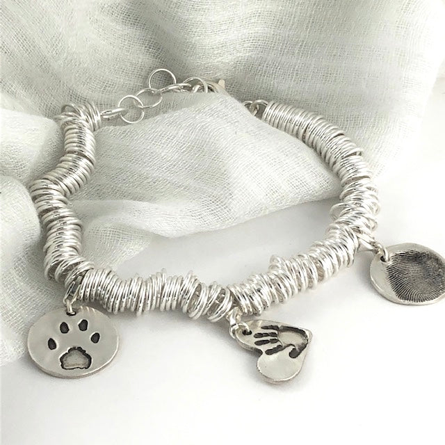 Sterling silver charm bracelet featuring hundreds of rings for elegant movement. Customizable with charms on lobster clasps for easy arrangement.