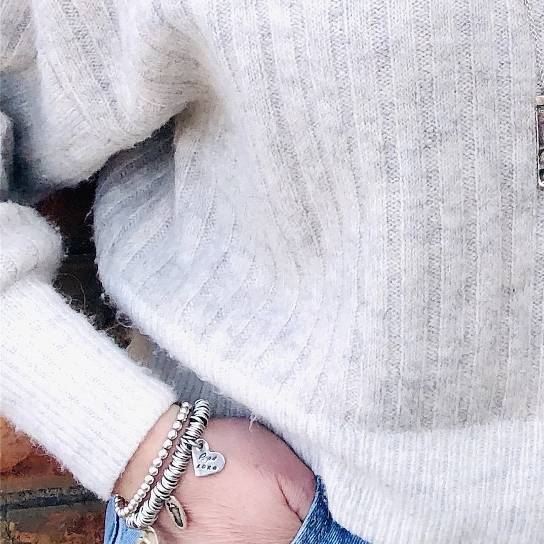 Sterling silver charm bracelet featuring hundreds of rings for elegant movement. Customizable with charms on lobster clasps for easy arrangement.