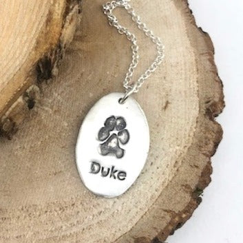 Fine silver oval shape pendant showcasing your pets pawprint. A sentimental keepsake, customizable with an optional chain or embellishment.